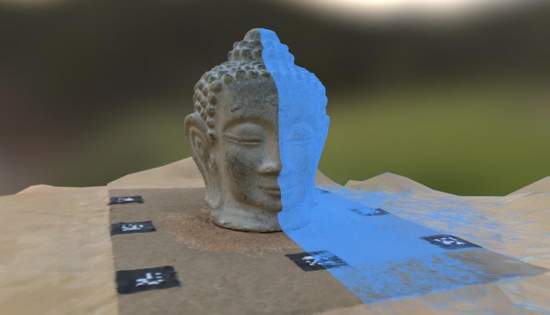 A carved head on a table, half of it shown as the reconstructed 3D mesh in blue